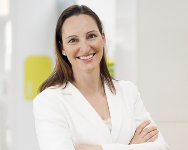 Frontaufnahme von Frau Simone Dünkler, die lächelnd mit verschränkten Armen in die Kamera schaut