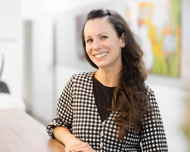 Frontaufnahme von Frau Simone Dünkler, die lächelnd mit verschränkten Armen in die Kamera schaut