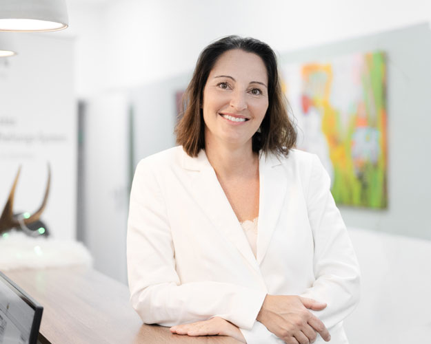 Frontaufnahme von Frau Simone Dünkler, die lächelnd mit verschränkten Armen in die Kamera schaut